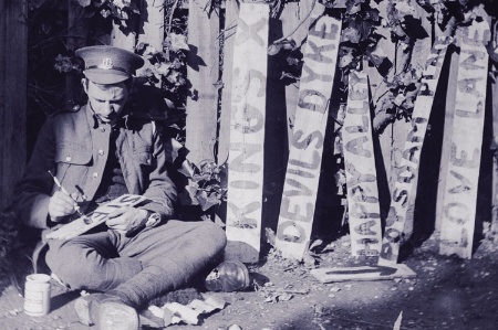Seated WWI soldier hand drawing signs