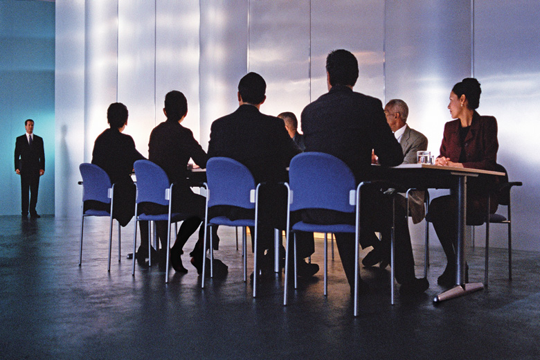 Businessman standing before table of executives Businessman standing before table of executives