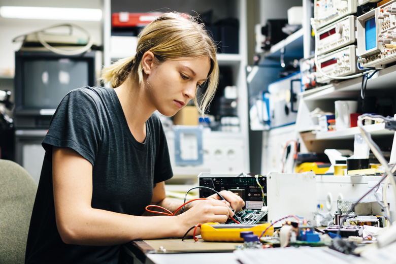 Female engineer measuring voltage on conductor board Female engineer measuring voltage on conductor board