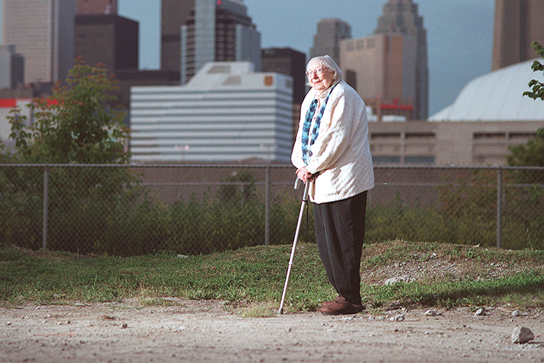 Jane Jacobs walking with city skyline in background Jane Jacobs walking with city skyline in background