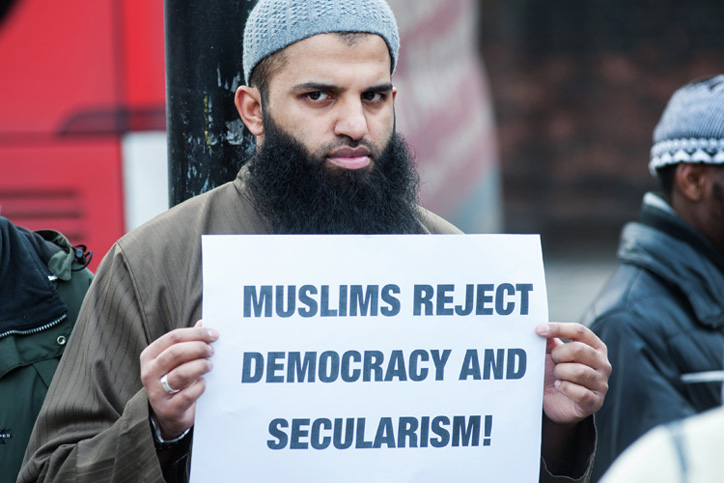 Man holding 'Muslims reject democracy and secularism' sign Man holding 'Muslims reject democracy and secularism' sign