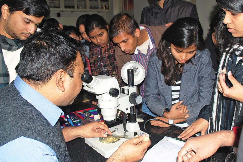 Students gather around a microscope Students gather around a microscope