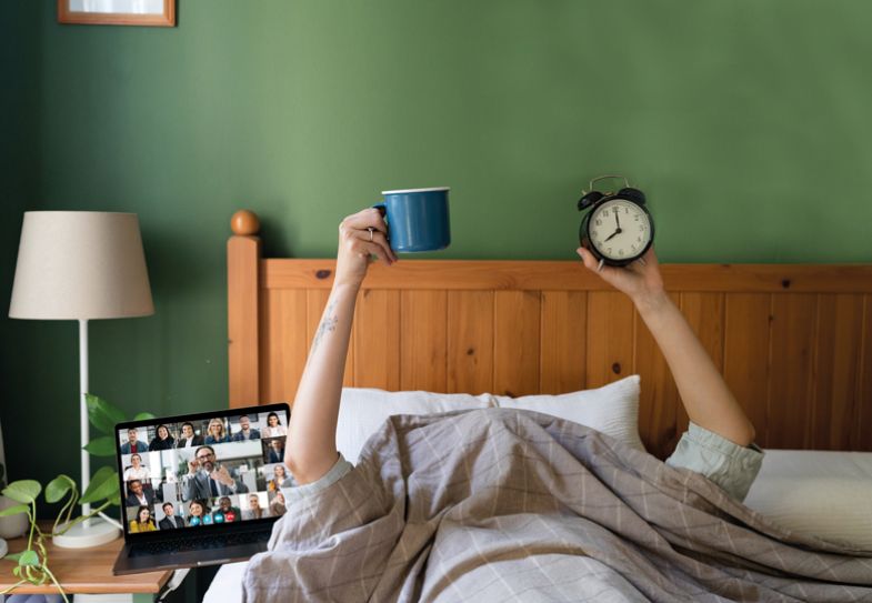 Montage of Hands of unrecognizable woman holding coffee and a clock while lying under the duvet in bed with a laptop next to her Montage of Hands of unrecognizable woman holding coffee and a clock while lying under the duvet in bed with a laptop next to her.jpg