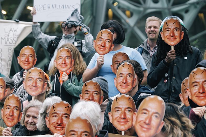 people wearing Jeff Bezos masks with devil horns drawn on people wearing Jeff Bezos masks with devil horns drawn on