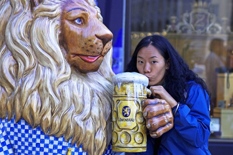 Chinese woman drinking from a fake beer glass, Munich, Germany. To illustrate that Asian students are being attracted to studying in Germany.