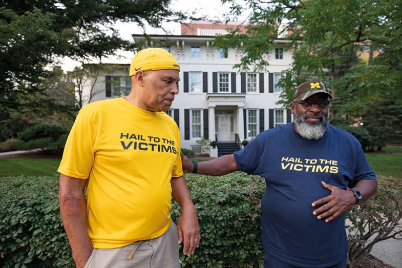 Chuck Christian (L) and former University of Michigan football player Jonathon Vaughn, who says he was sexually assaulted by former UM sports doctor Robert Anderson, take part in a vigil outside the home of outgoing University of Michigan President Mark S Chuck Christian (L) and former University of Michigan football player Jonathon Vaughn, who says he was sexually assaulted by former UM sports doctor Robert Anderson, take part in a vigil outside the home of outgoing University of Michigan President Mark S