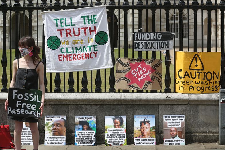 A climate change protester holds a sign saying 'Fossil Free Research' in front of the railings of the University's Senate House in Cambridge, England A climate change protester holds a sign saying 'Fossil Free Research' in front of the railings of the University's Senate House in Cambridge, England