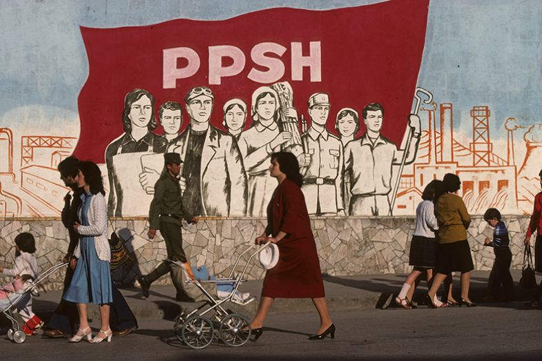 Korcia, Albania at the end of the communist regime. Pedestrians pass by a realistic socialist-style painting, with a slogan: “Glory to the Communist Party” Korcia, Albania at the end of the communist regime. Pedestrians pass by a realistic socialist-style painting, with a slogan: “Glory to the Communist Party”