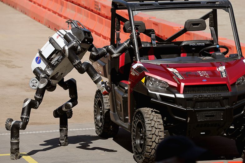 The Jet Propulsion Labs’ Team RoboSimian 275-pound robot climbs out of a Polaris vehicle after driving through obstacles during the Defense Advanced Research Projects Agency (Darpa) Robotics Challenge, showcasing artificial intelligence.