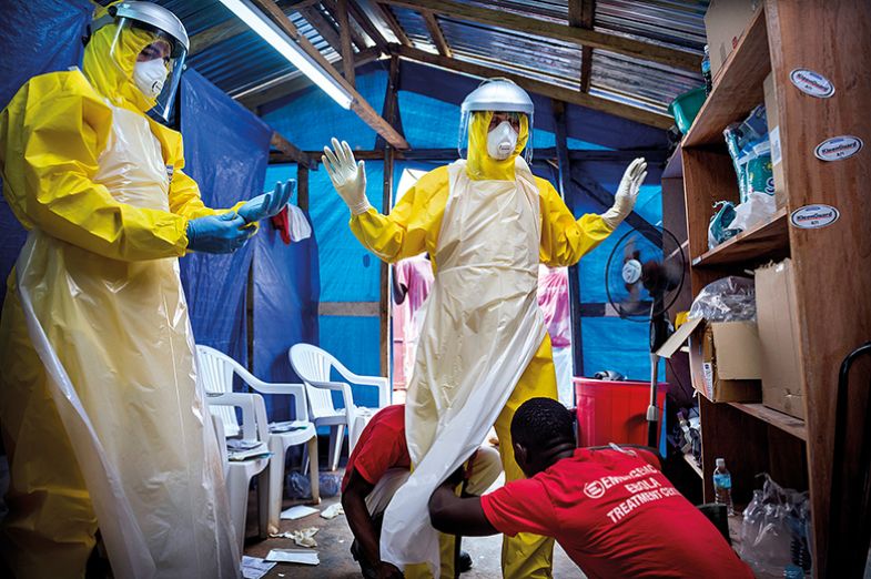 Western aid workers are helped into their PPE by two local staff at an ebola treatment centre in Sierra Leone Western aid workers are helped into their PPE by two local staff at an ebola treatment centre in Sierra Leone