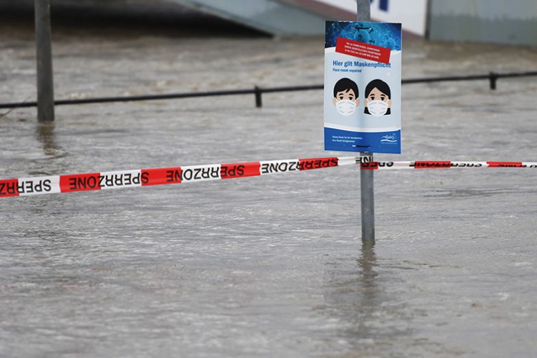 A sign for the compulsory wearing of face masks during the coronavirus pandemic is seen on the banks of the flooded Rhine river in Koenigswinter, western Germany, on February 3, 2021 A sign for the compulsory wearing of face masks during the coronavirus pandemic is seen on the banks of the flooded Rhine river in Koenigswinter, western Germany, on February 3, 2021