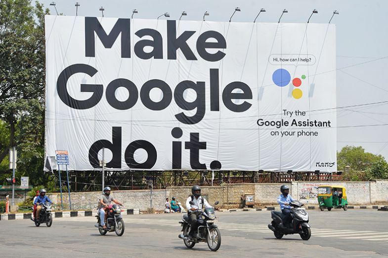 Indian commuters ride past a poster for Google in Bengaluru in 2018, symbolising the power of the company.