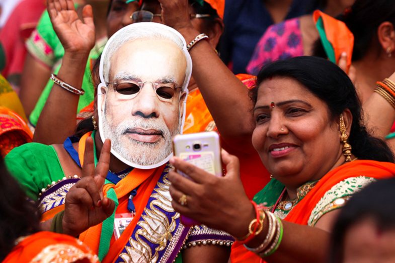 Supporters of the ruling BJP, with one wearing a mask of prime minister Narendra Modi, take a selfie.