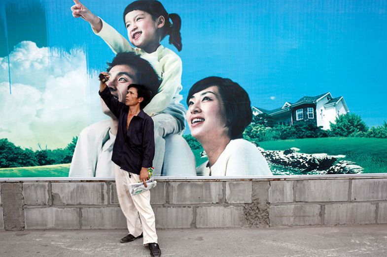 Man takes photo in front of poster of one-child family, Shanghai, China Man takes photo in front of poster of one-child family, Shanghai, China