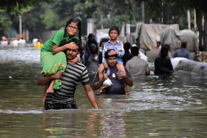 Indian residents carry children as they walk through floodwaters in Chennai on December 3, 2015 Indian residents carry children as they walk through floodwaters in Chennai on December 3, 2015