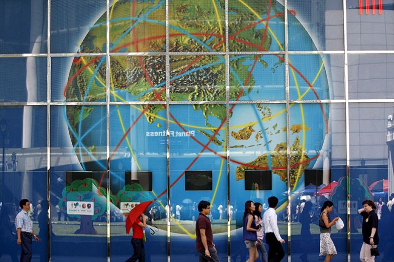 Office workers walk past a large billboard of a globe with connection routes in the financial district of Singapore. To illustrate transnational education and how other destinations may provide better growth opportunities than Singapore. Office workers walk past a large billboard of a globe with connection routes in the financial district of Singapore. To illustrate transnational education and how other destinations may provide better growth opportunities than Singapore.