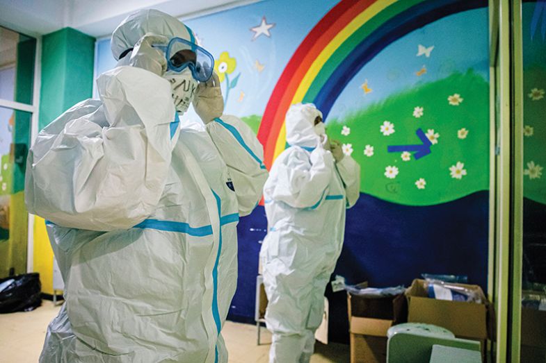 People in PPE in front of a rainbow mural People in PPE in front of a rainbow mural