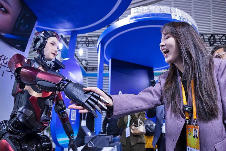 A visitor shakes hands with a humanoid robot at the Light of Internet Expo, showcasing the latest technological achievements in artificial intelligence, on 19 November 2024 in Wuzhen, Jiaxing City, Zhejiang Province of China. 