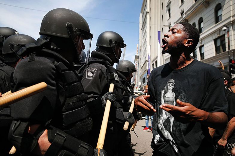 Man in front of riot police during rally in solidarity with Charlottesville, US Man in front of riot police during rally in solidarity with Charlottesville, US