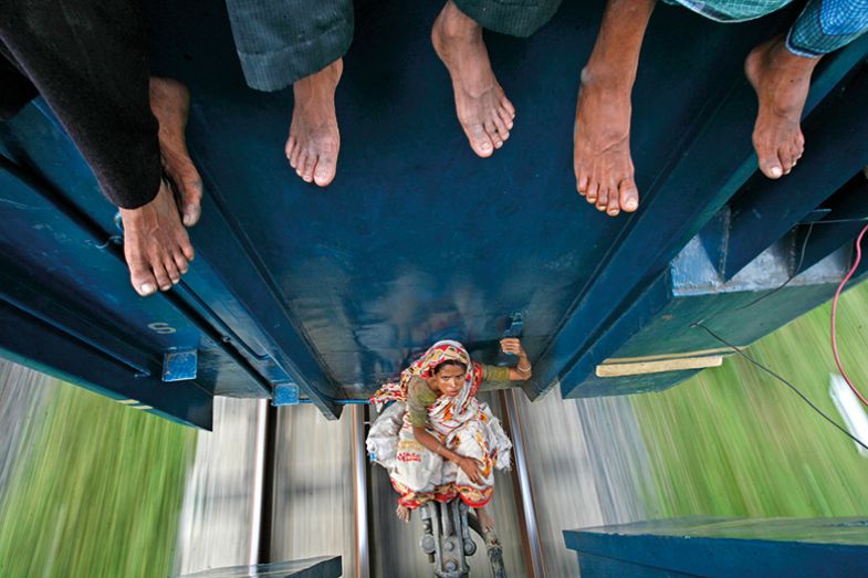 A woman sits between carriages as the train travels to Mymensing from Dhaka September 20, 2009. A woman sits between carriages as the train travels to Mymensing from Dhaka September 20, 2009.