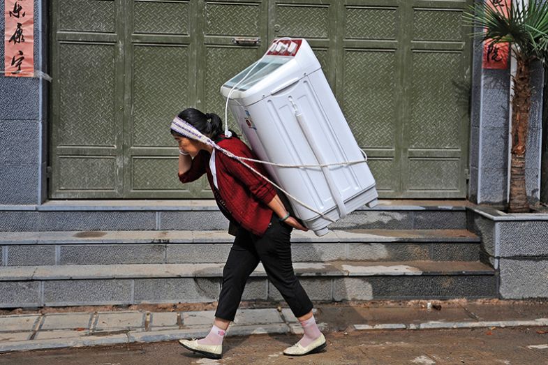 A woman carries home a washing machine in Dali, Yunnan province July 30, 2013. A woman carries home a washing machine in Dali, Yunnan province July 30, 2013.