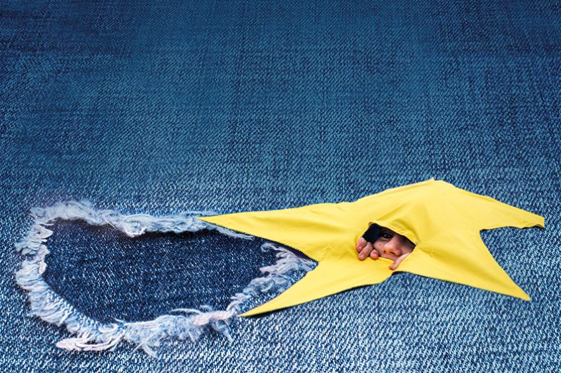 Montage of person peeping from European Union star and torn denim Montage of person peeping from European Union star and torn denim