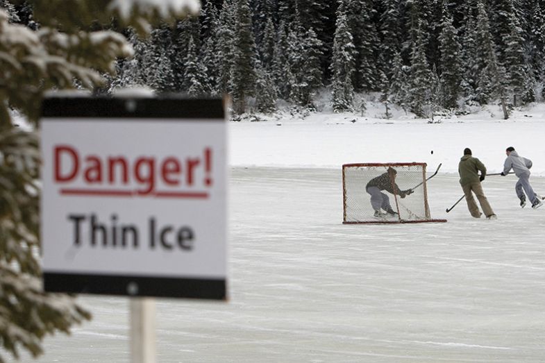A group of skaters play pond hockey on Lake Louise, with a "Danger! Thin ice" sign. A group of skaters play pond hockey on Lake Louise, with a "Danger! Thin ice" sign.