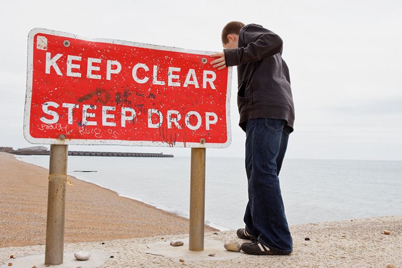 Person near edge with "Keep Clear. Steep drop" sign Person near edge with "Keep Clear. Steep drop" sign