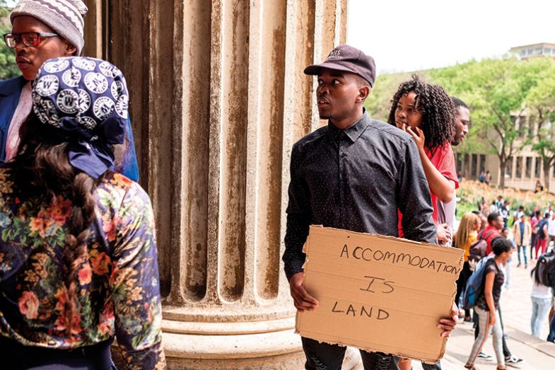 A student holds a placard that reads "Accommodation is Land" on the WITS University Campus in Johannesburg's central suburb of Braamfontein A student holds a placard that reads "Accommodation is Land" on the WITS University Campus in Johannesburg's central suburb of Braamfontein