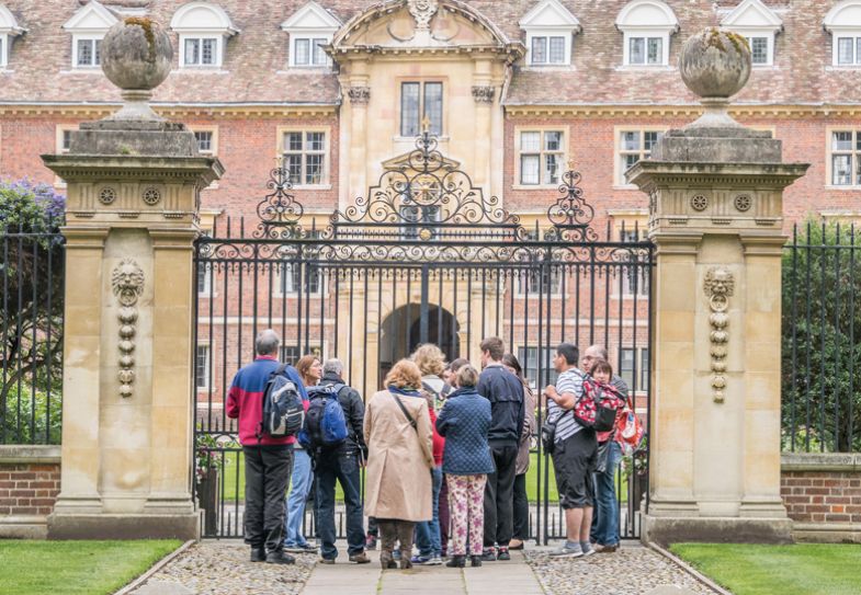 A group of tourists stand outside the gated entrance to St Catherine's college, university of Cambridge, England. A group of tourists stand outside the gated entrance to St Catherine's college, university of Cambridge, England to illustrate it being closed for admissions