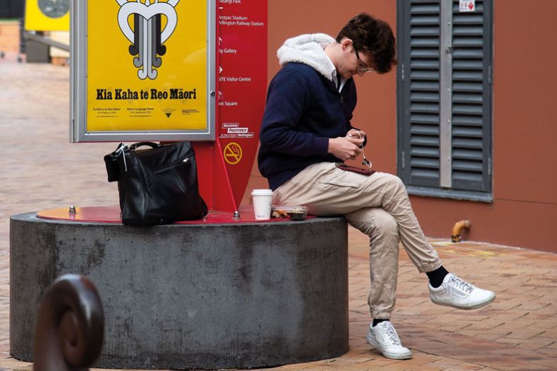 A man sits next to a Maori language sign A man sits next to a Maori language sign