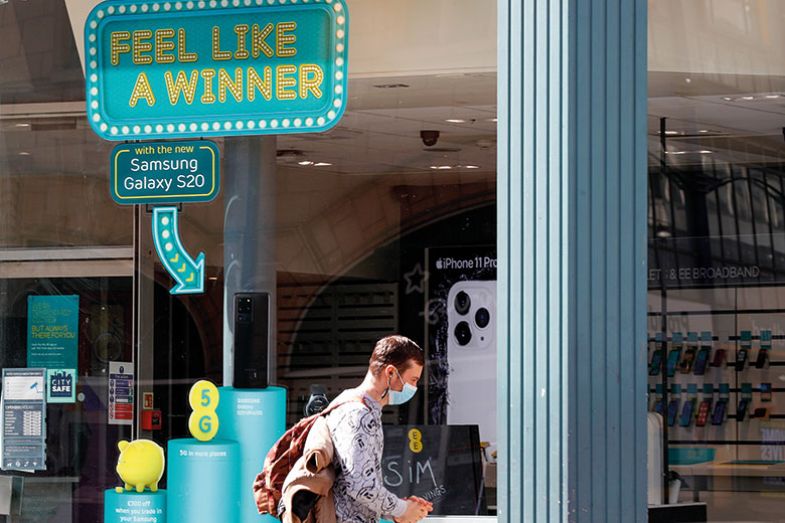 pedestrian, wearing a protective mask, walks past a window with feel like a winner sign. pedestrian, wearing a protective mask, walks past a window with feel like a winner sign.