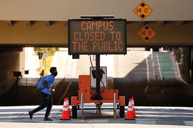 Person walks past Campus Closed to public sign. Person walks past Campus Closed to public sign.
