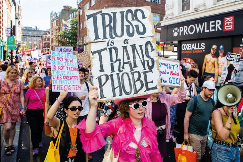 Protester holding banner reading 'Truss is a transphobe' during a protest Protester holding banner reading 'Truss is a transphobe' during a protest as described in the copy