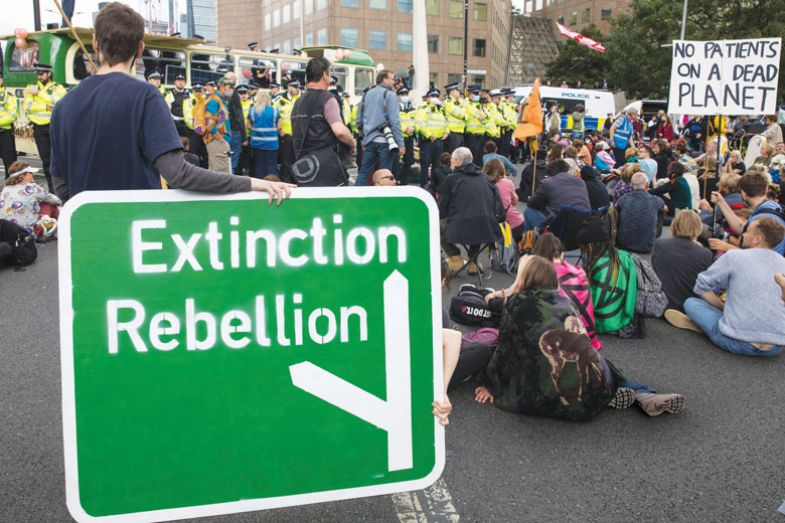 Protestor holding large Extinction Rebellion road sign during a protest Protestor holding large Extinction Rebellion road sign during a protest