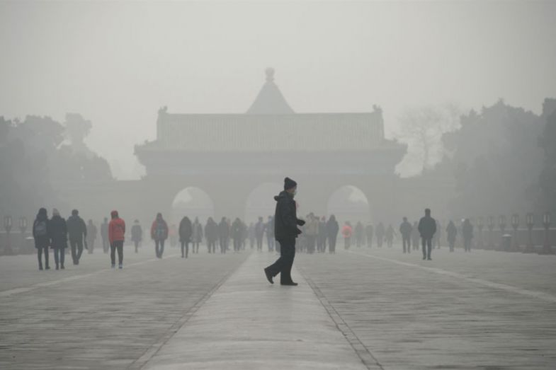 A man walks in front of a group of people during heavy smog at a the Temple of Heaven park in Beijing A man walks in front of a group of people during heavy smog at a the Temple of Heaven park in Beijing