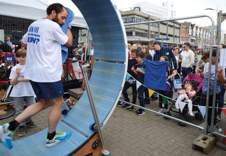 Person running in a a six feet diameter wooden 'hamster wheel' in Southend, UK Person running in a a six feet diameter wooden 'hamster wheel' in Southend, UK