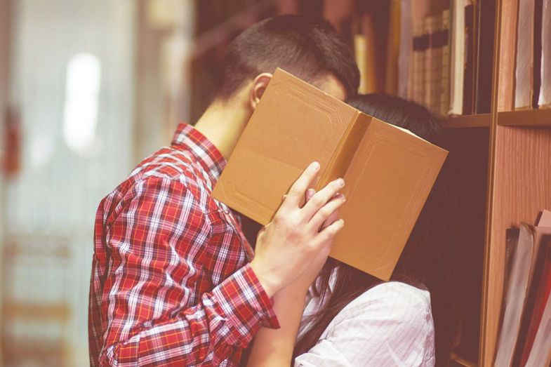 Photo of man and woman kissing in library and close their face by book Photo of man and woman kissing in library and close their face by book for Getting back to the stacks.