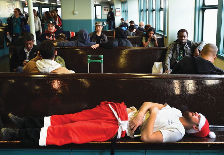 A man dressed in a Santa outfit sleeps on the Staten Island during the SantaCon in New York City A man dressed in a Santa outfit sleeps on the Staten Island during the SantaCon in New York City to illustrate exhaustion