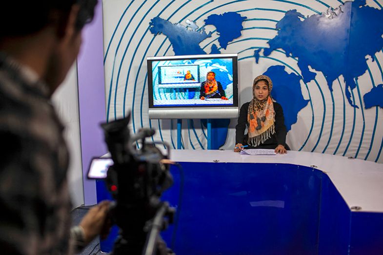 A female news presenter sits at a desk during a television broadcast in a studio in Herat, Afghanistan on 17 July 2012.
