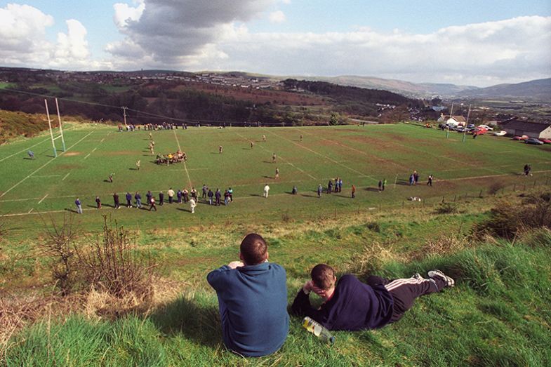 Two youths watch a rugby match near Merthyr Tydfil, South Wales. Illustrating low participation rates in higher education in Wales. Two youths watch a rugby match near Merthyr Tydfil, South Wales. Illustrating low participation rates in higher education in Wales.