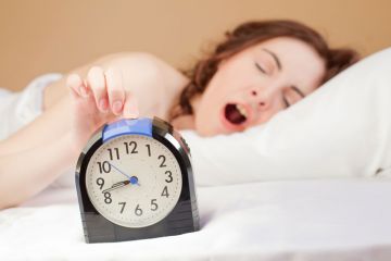 Yawning woman pressing alarm snooze button Yawning woman pressing alarm snooze button