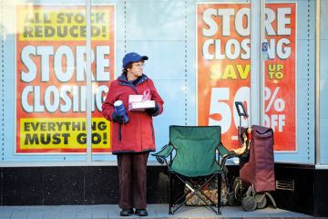 A charity collector standing outside a shop A charity collector standing outside a shop