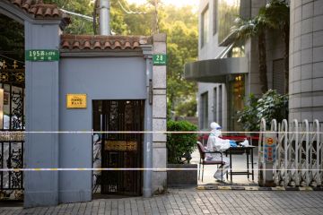 A 'big white' volunteer sits at a compound gate in Shanghai, Xuhui district during 4 day city wide lockdown as it drags on past the planned finish date as Shanghai struggles to control a large outbreak of COVID-19.