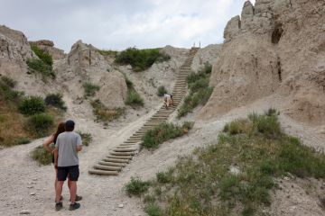 A hiker climbing the ladder of the Notch Trail at Badlands National Park, South Dakota