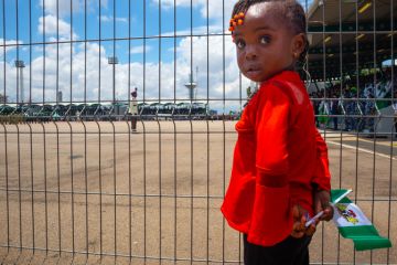 A young girl was seen holding Nigeria Flag behind a barricade during 62nd independence day celebration at eagle square, Abuja, Nigeria A young girl was seen holding Nigeria Flag behind a barricade during 62nd independence day celebration at eagle square, Abuja, Nigeria