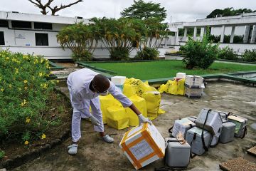 African worker in PPE inspects supplies