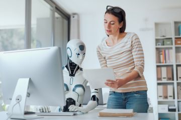 A woman talks to a robot about a paper, symbolising the trialling of AI peer review