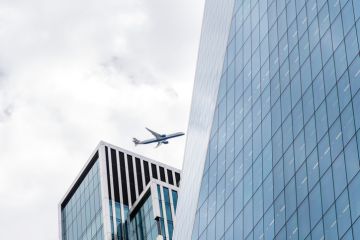 Airplane flying among skyscrapers in view of modern office buildings in the City of London