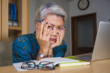 A woman reading a book with her head in her hands